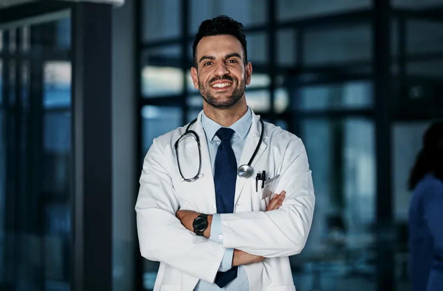Médico confiante de jaleco branco com estetoscópio, braços cruzados